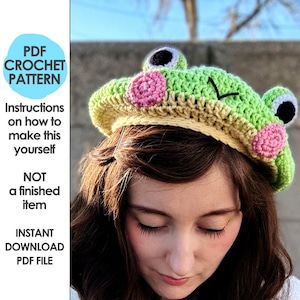 May include: A green and yellow crocheted frog hat with pink accents and black details. The hat has large, round eyes and is worn by a person. The image also includes text that says "PDF CROCHET PATTERN".