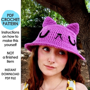 May include: A crochet pattern for a purple bucket hat with cat ears and a black "uwu" design. The pattern is available for instant download as a PDF file.