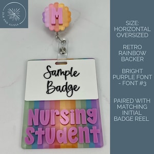 May include: A horizontal oversized badge reel featuring a scalloped rainbow-colored topper with a pink letter M. The badge displays the text Sample Badge in black script and Nursing Student in bright purple block letters on a rainbow background.