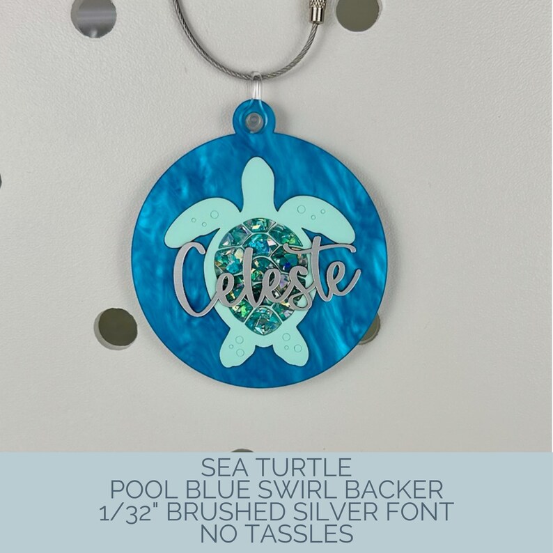 May include: A round, blue swirl-patterned tag with a sea turtle design. The tag features the name "Celeste" in silver lettering and is attached to a silver-colored wire. The text at the bottom reads "SEA TURTLE POOL BLUE SWIRL BACKER 1/32" BRUSHED SILVER FONT NO TASSLES."