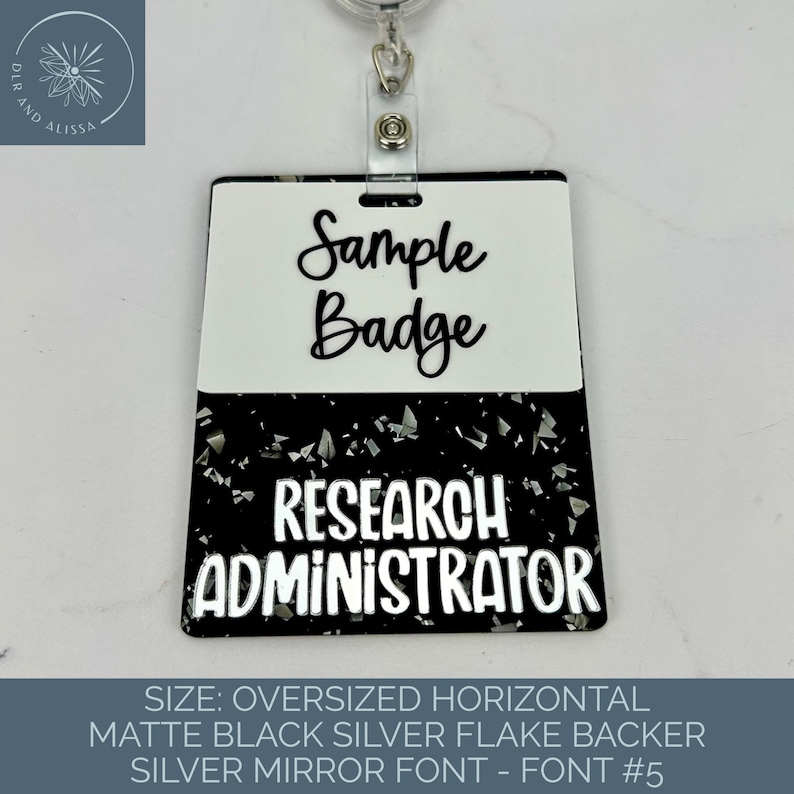 May include: A rectangular badge with a white top section featuring the black text Sample Badge and a black bottom section with silver flakes featuring the white text RESEARCH ADMINISTRATOR, attached to a silver metal retractable clip.