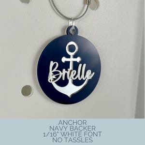 May include: Navy blue and white anchor-themed tag with the name "Brielle" in a white font. The tag is round and attached to a silver wire. The text at the bottom reads "ANCHOR NAVY BACKER 1/16" WHITE FONT NO TASSLES."