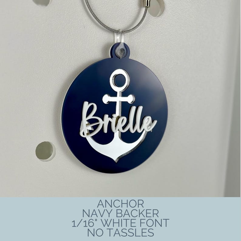 May include: Navy blue and white anchor-themed tag with the name "Brielle" in a white font. The tag is round and attached to a silver wire. The text at the bottom reads "ANCHOR NAVY BACKER 1/16" WHITE FONT NO TASSLES."