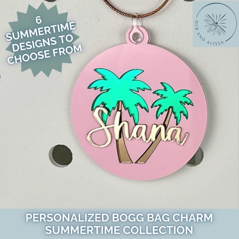 May include: A pink circular bag charm with a palm tree design and the name "Shana" in gold. The charm is part of the "Summertime Collection" and features the text "6 Summertime Designs to Choose From".