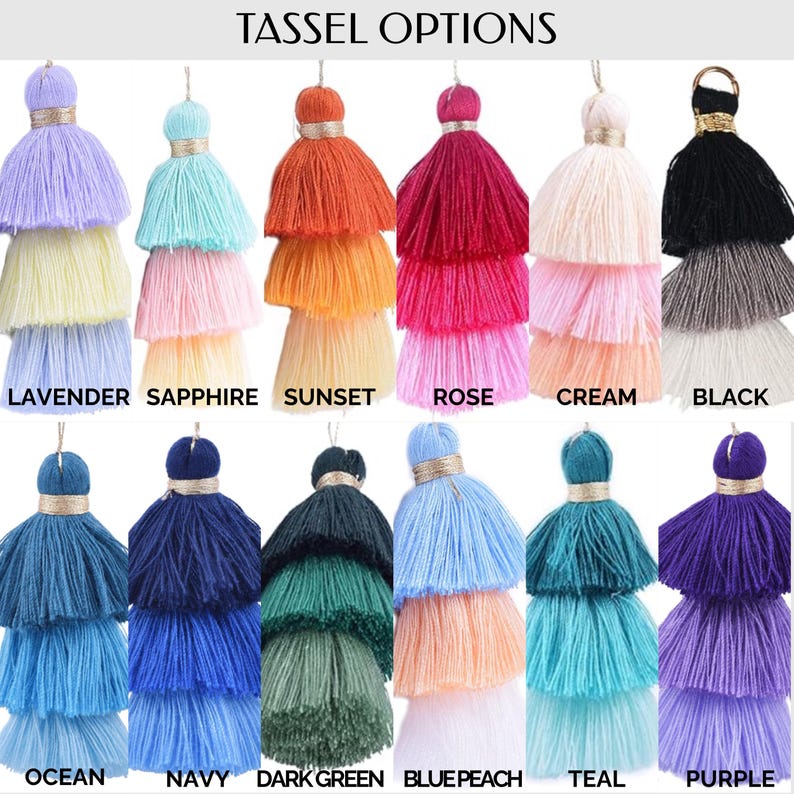 May include: A collection of colorful layered tassels in various shades, including lavender, sapphire, sunset, rose, cream, black, ocean, navy, dark green, blue peach, teal, and purple. Each tassel has a gold-colored top and is labeled with its color name.