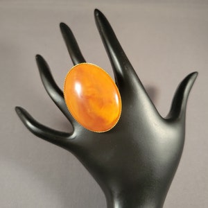 May include: A large, oval-shaped ring with a gold setting and a brown and orange stone.