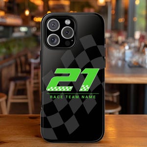 May include: Black phone case featuring a green and white number 21 with a checkered flag design. The words "RACE TEAM NAME" are printed below the number. The case has a glossy finish and covers the back and sides of the phone.