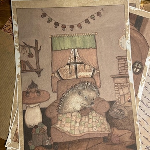 Peut inclure: Plusieurs tirages d'art représentant un hérisson se relaxant dans un fauteuil confortable près d'une fenêtre. La scène comprend une cheminée, une guirlande de champignons et une petite table avec un dessus en forme de champignon. L'œuvre a une palette de couleurs chaleureuse.