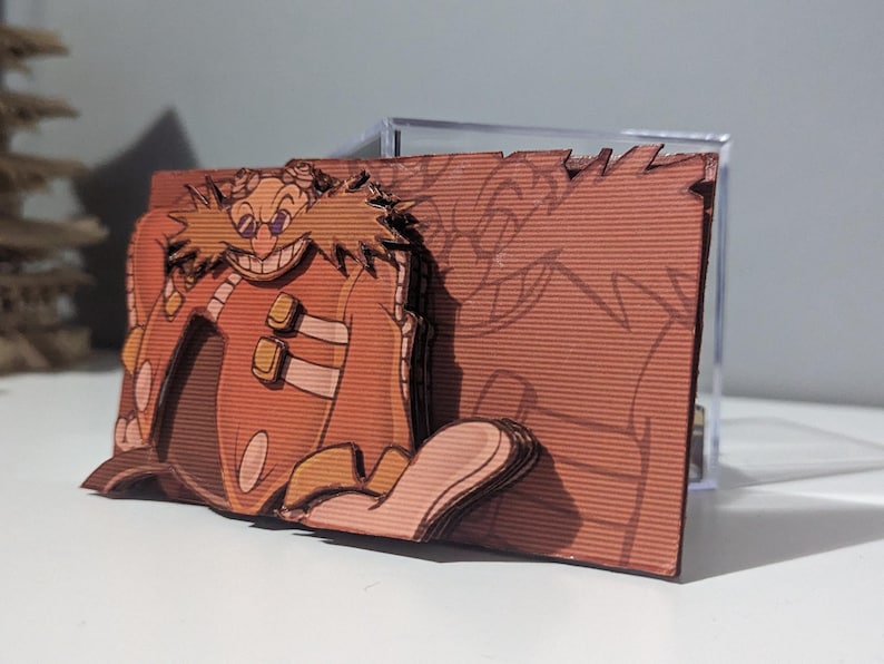 May include: A 3D papercraft model of Dr. Eggman, a villain from the Sonic the Hedgehog video game series. The model is made of brown cardboard and features a detailed depiction of Dr. Eggman's face and mustache.