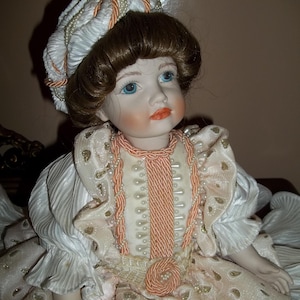 collectible doll in biscuit porcelain with fine fabrics and decorations