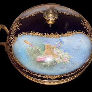 Può includere: Piatto da portata antico in porcellana con esterno blu scuro e una scena dipinta a mano di un cesto di fiori e un cappello. Il piatto ha manici e finiture color oro e un pomello in ottone sul coperchio.