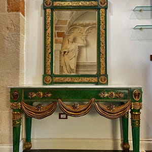 May include: A green and gold console table with a matching mirror. The table has a white marble top, green legs, and gold decorative accents. The mirror is framed in green and gold, with a shell-shaped top.