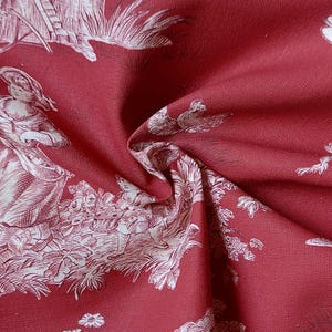 Può includere: Un tessuto rosso intenso caratterizzato da un motivo toile de jouy bianco. Il design presenta intricate illustrazioni a linee di figure in abiti d'epoca, grappoli di fiori e fogliame, creando una scena ripetuta sulla superficie tessile.