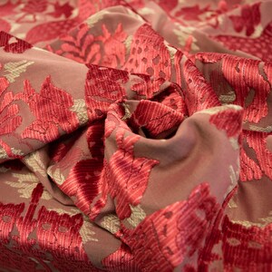 Pode incluir: Close-up de um tecido rosa com um padr&atilde;o floral vermelho. O tecido tem uma textura aveludada.