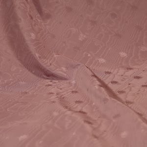 May include: A dusty rose fabric featuring a subtle, repeating floral pattern and a wavy, rippled texture. The material is draped to show soft folds, highlighting the tonal design and the consistent, muted pink color throughout the textile surface.