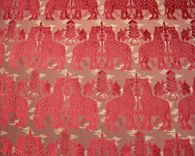 Pode incluir: Tecido vermelho com um padr&atilde;o repetido de elefantes estilizados. Os elefantes s&atilde;o delineados em um vermelho mais escuro e t&ecirc;m uma apar&ecirc;ncia texturizada.