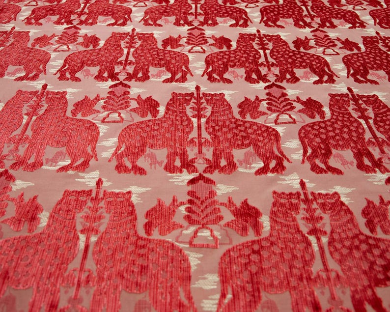 Pode incluir: Tecido vermelho com um padr&atilde;o repetido de leopardos estilizados e &aacute;rvores. O tecido tem uma apar&ecirc;ncia texturizada, quase aveludada.