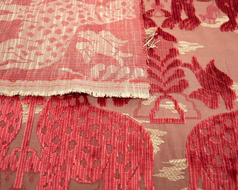 Pode incluir: Duas pe&ccedil;as de tecido vermelho com um padr&atilde;o de cor creme. A pe&ccedil;a superior tem um padr&atilde;o mais intrincado com um design floral. A pe&ccedil;a inferior tem um padr&atilde;o mais simples com um design geom&eacute;trico.