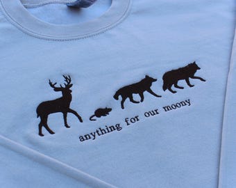 May include: Light blue long-sleeved sweatshirt with a black embroidered design of a deer, a rat, two wolves, and the text "anything for our moony".