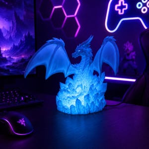 May include: A translucent blue dragon figurine illuminated from within, featuring large spread wings and a textured body perched atop a cluster of jagged, crystalline structures that emit a bright, glowing light in a dark environment.
