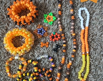May include: A collection of Halloween and Fall Kandi jewelry including beaded bracelets, necklaces, and charms in orange, black, yellow, white, and purple. The set features a long necklace with a star pendant and text reading Halloween - Fall Kandi bundle.