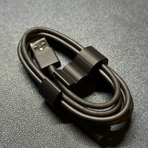 Puede incluir: Un cable USB negro con una brida de cable negra que lo mantiene unido.