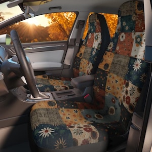 Könnte beinhalten: Ein Paar Autositzbezüge mit einem Patchwork-Design aus verschiedenen Blumenmustern in Orange, Dunkelblau, Braun und Creme. Die Bezüge sind über die Vordersitze eines Fahrzeugs gezogen und zeigen ein wiederkehrendes Motiv von Gänseblümchen.