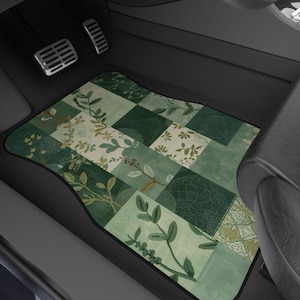 May include: A car floor mat featuring a patchwork design of various shades of green and cream. The pattern consists of alternating squares displaying botanical illustrations of leaves, vines, and intricate geometric textures on a fabric surface.
