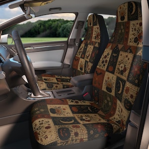 May include: A pair of car seat covers featuring a patchwork design with various rectangular panels. The pattern includes illustrations of pumpkins, cauldrons, crescent moons, bats, and floral arrangements in shades of orange, brown, and black.