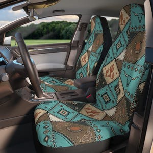 Peut inclure: Une paire de housses de siège auto avec un motif patchwork en losanges dans des tons turquoise, marron et crème. L'imprimé comprend des illustrations de crânes de longhorn, de fers à cheval, de cactus et de formes géométriques avec une bordure.