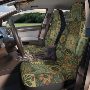 Peut inclure: Une paire de housses de siège auto présentant un motif patchwork avec divers designs floraux et botaniques dans des tons vert sauge, jaune moutarde et orange brûlé. Les housses sont installées sur les sièges avant d'un véhicule avec un volant.