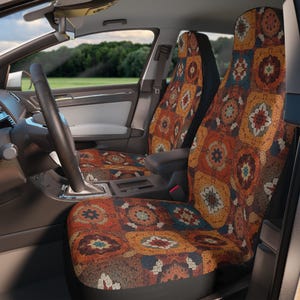 Peut inclure: Housses de siège de voiture avec un motif patchwork dans les tons orange, marron, jaune et bleu. Les housses présentent un motif répétitif de motifs carrés avec des éléments floraux et géométriques. L'intérieur d'une voiture est visible, avec un volant et un tableau de bord.