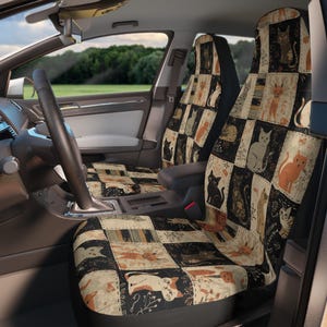 May include: A pair of car seat covers featuring a patchwork design of various cat illustrations in shades of black, cream, orange, and gray. The fabric pattern consists of rectangular blocks, each displaying a different feline pose, floral motifs, and decorative line work, covering the front and back of the vehicle seats.