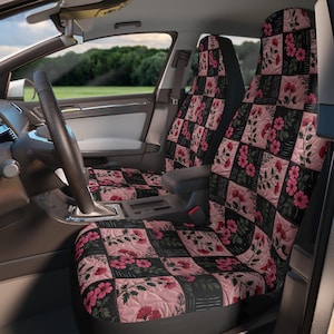 May include: A pair of car seat covers featuring a quilted patchwork design. The pattern alternates between squares of solid black and squares of light pink, each decorated with a detailed illustration of pink flowers and green stems and leaves.