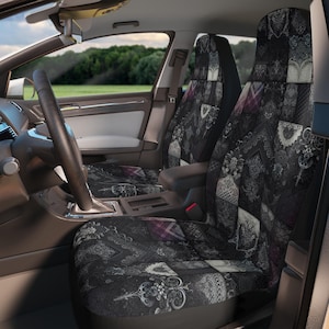 May include: A pair of car seat covers featuring a dark, intricate patchwork design in shades of black, grey, and muted purple. The pattern consists of various ornate floral, lace, and geometric motifs arranged in a grid-like layout across the fabric.