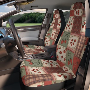 Pode incluir: Um par de capas para assentos de carro com um design de patchwork de morangos vermelhos em vinhas verdes, padrões xadrez e seções vermelhas sólidas. O tecido cobre toda a frente e as costas dos assentos, exibindo uma estampa botânica.