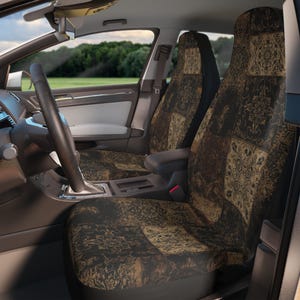 May include: A pair of car seat covers featuring a dark brown and tan patchwork design with intricate floral and damask patterns. The covers are fitted over the front seats of a vehicle, displaying a repeating square motif across the backrests.