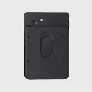 May include: A black rectangular device with a rounded top and a recessed oval shape in the centre. It has a small camera lens and a light-coloured dot near the top. The device has four small screws and the letters "LPH" are visible at the bottom.