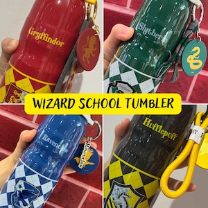 Puede incluir: Cuatro botellas de agua de acero inoxidable con diferentes escudos y colores de las casas de Hogwarts. Las botellas están etiquetadas con los nombres de las casas: Gryffindor, Slytherin, Hufflepuff y Ravenclaw. Cada botella tiene un amuleto a juego con el escudo de la casa.