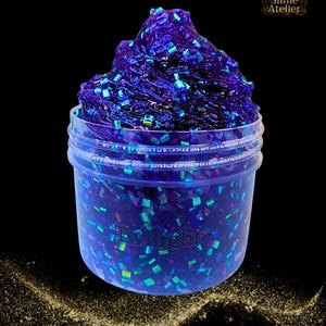 Peut inclure: Un pot de slime violet avec des paillettes irisées. Le slime est d'un violet profond et a une texture brillante. Les paillettes sont un mélange de bleu, de vert et de violet. Le pot est en plastique transparent et a un couvercle. Le texte "Twilight" est visible.