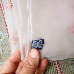 Può includere: Sciarpa bianca in chiffon con stampa floreale rossa. La sciarpa ha un'etichetta blu che recita "Yuky Dee All Nylon Exclusive of Decoration Made in Japan RN 11696".
