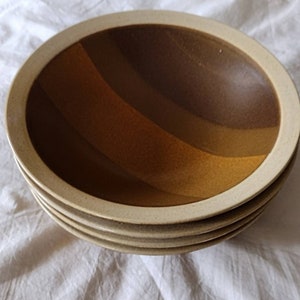 May include: A stack of four brown and white ceramic bowls with a wavy, layered design. The bowls are nested together.