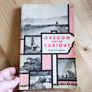 Puede incluir: Una portada de libro vintage con fondo rosa y texto negro que dice "Oregon for the Curious" de Ralph Friedman. La portada presenta fotos en blanco y negro de paisajes de Oregón, incluyendo una carretera, un bosque, una casa y un faro.
