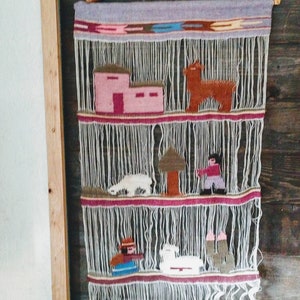 May include: A woven wall hanging with a light gray background and colorful geometric patterns. The hanging features various figures, including a house, a tree, and animals, all woven into the fabric.
