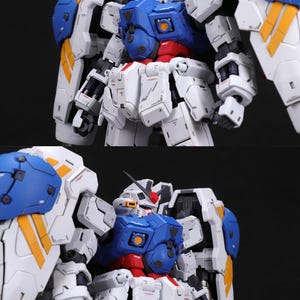 Puede incluir: Modelo detallado de un robot, con una combinaci&oacute;n de colores blanco, azul, rojo y amarillo. El robot tiene una gran armadura en los hombros y detalles mec&aacute;nicos intrincados. El modelo est&aacute; sobre un fondo oscuro.