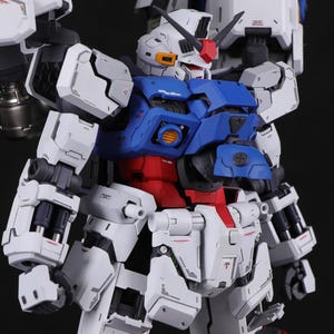 Puede incluir: Modelo detallado de un robot con una combinaci&oacute;n de colores blanco, azul y rojo. El robot presenta intrincados detalles mec&aacute;nicos, incluyendo paneles, articulaciones y una cabeza con una cresta roja. Fondo oscuro.