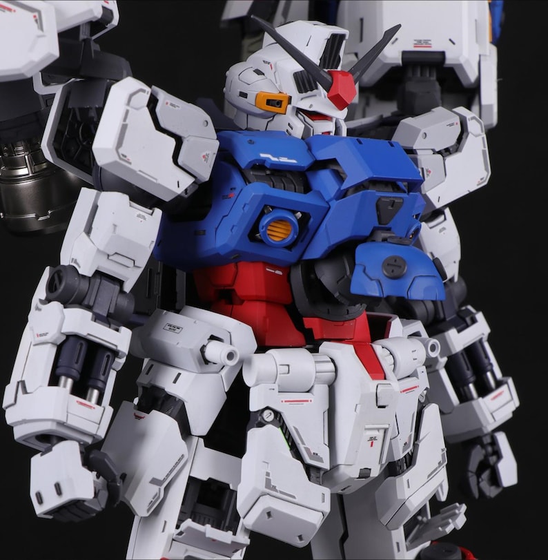 Puede incluir: Modelo detallado de un robot con una combinaci&oacute;n de colores blanco, azul y rojo. El robot presenta intrincados detalles mec&aacute;nicos, incluyendo paneles, articulaciones y una cabeza con una cresta roja. Fondo oscuro.