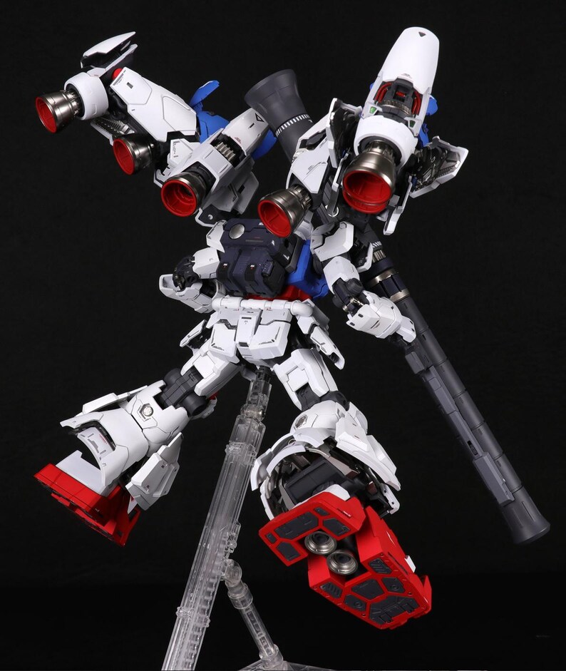 Puede incluir: Maqueta detallada y ensamblada de un robot mec&aacute;nico blanco y azul con detalles en rojo. El robot presenta m&uacute;ltiples propulsores, un arma grande y est&aacute; montado sobre un soporte transparente sobre un fondo negro. El modelo es muy detallado.