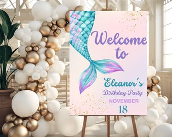 May include: Welcome to Eleanor's Birthday Party sign with a purple and teal mermaid tail illustration on a pink and gold background with gold glitter. The text is in purple and blue.