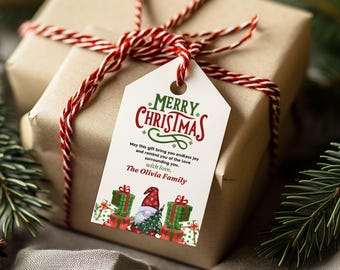 Könnte beinhalten: Ein weißer Geschenkanhänger mit einem rot-grünen Frohe Weihnachten-Design. Der Anhänger zeigt einen Gnom mit roter Mütze und grünem Bart, umgeben von verpackten Geschenken. Der Text lautet "Frohe Weihnachten" und "Möge dieses Geschenk dir endlose Freude bringen und dich an die Liebe erinnern, die dich umgibt. Mit Liebe, Die Familie Olivia."